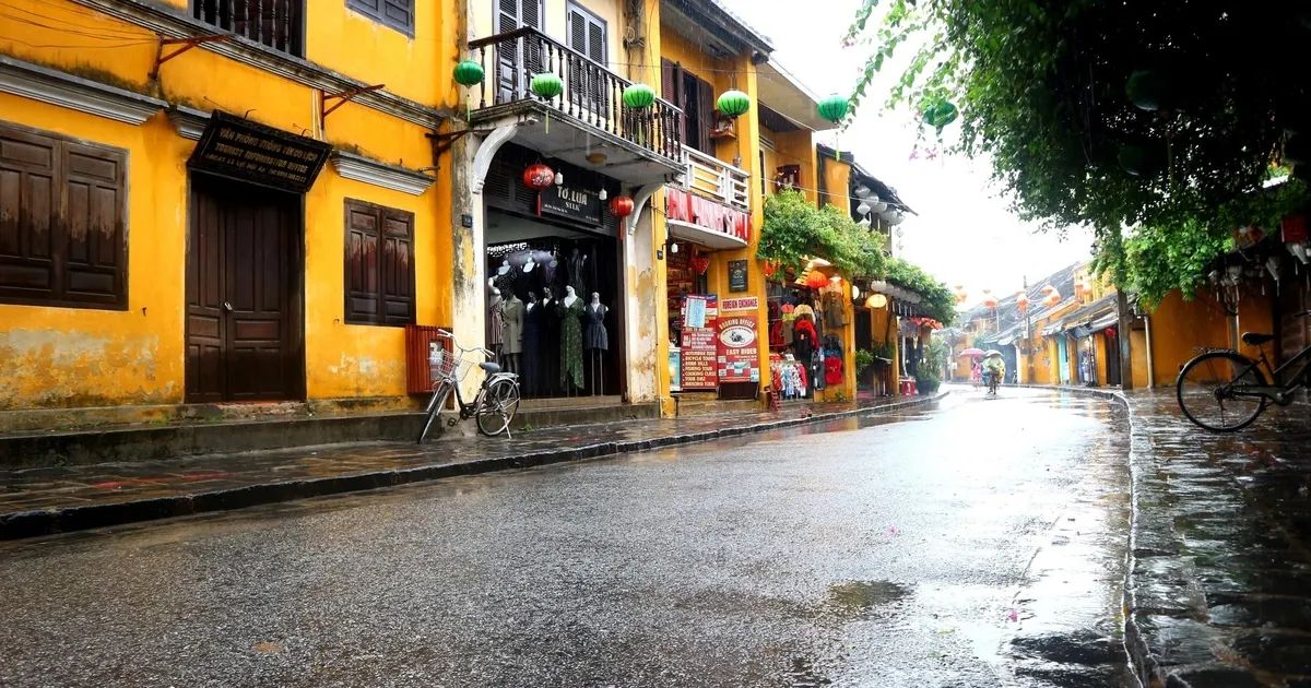 Du khách đi trong mưa phùn Hội An với áo khoác màu