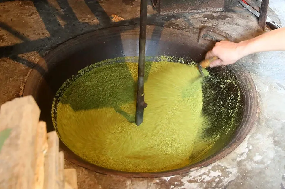 Người thợ rang cốm trên chảo gang với ngọn lửa nhỏ