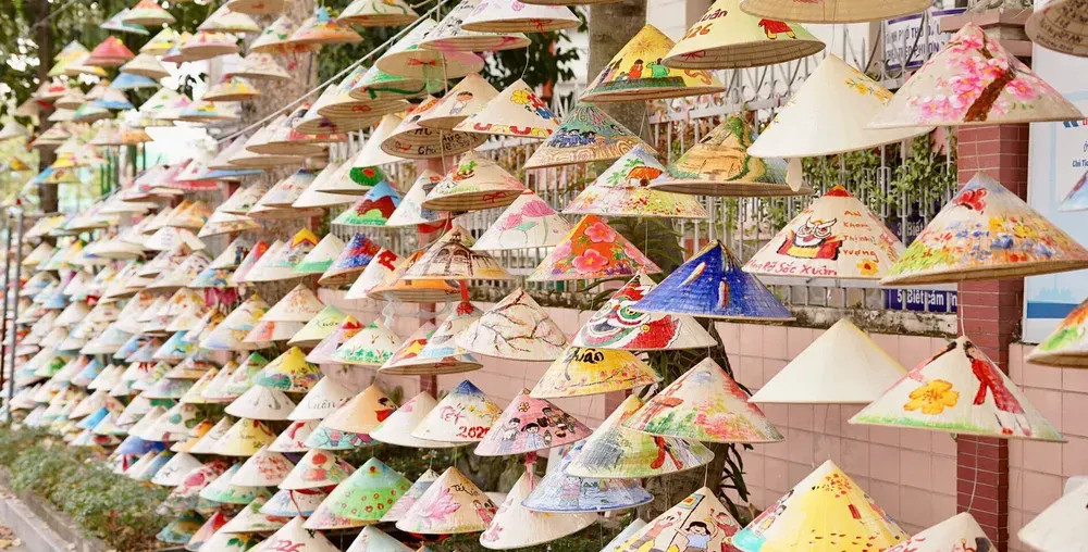 Du khách mang nón lá tự làm đi qua con đường làng vào buổi chiều