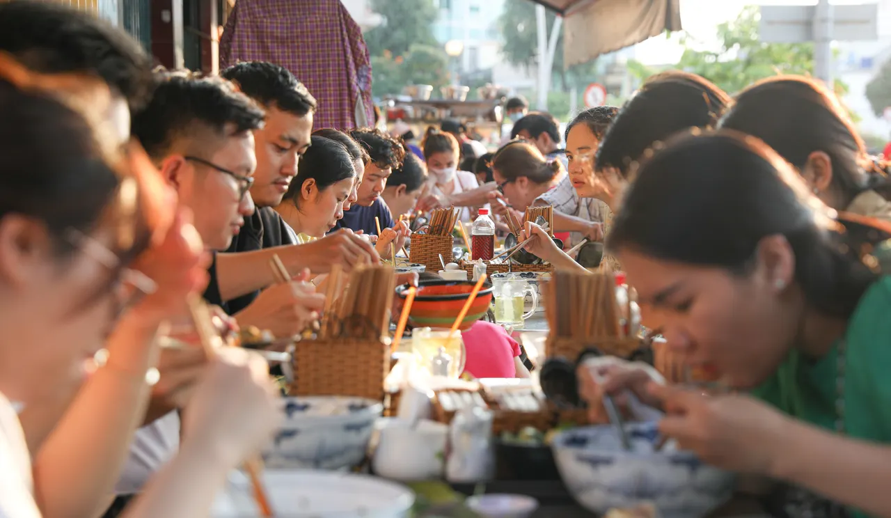 Du khách ngồi ăn bún bò tại quán vỉa hè cùng người dân địa phương