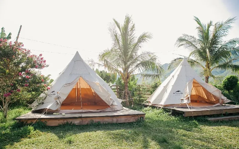 Khu glamping giữa đồi cỏ vào mùa thu đông với lều và đèn trang trí